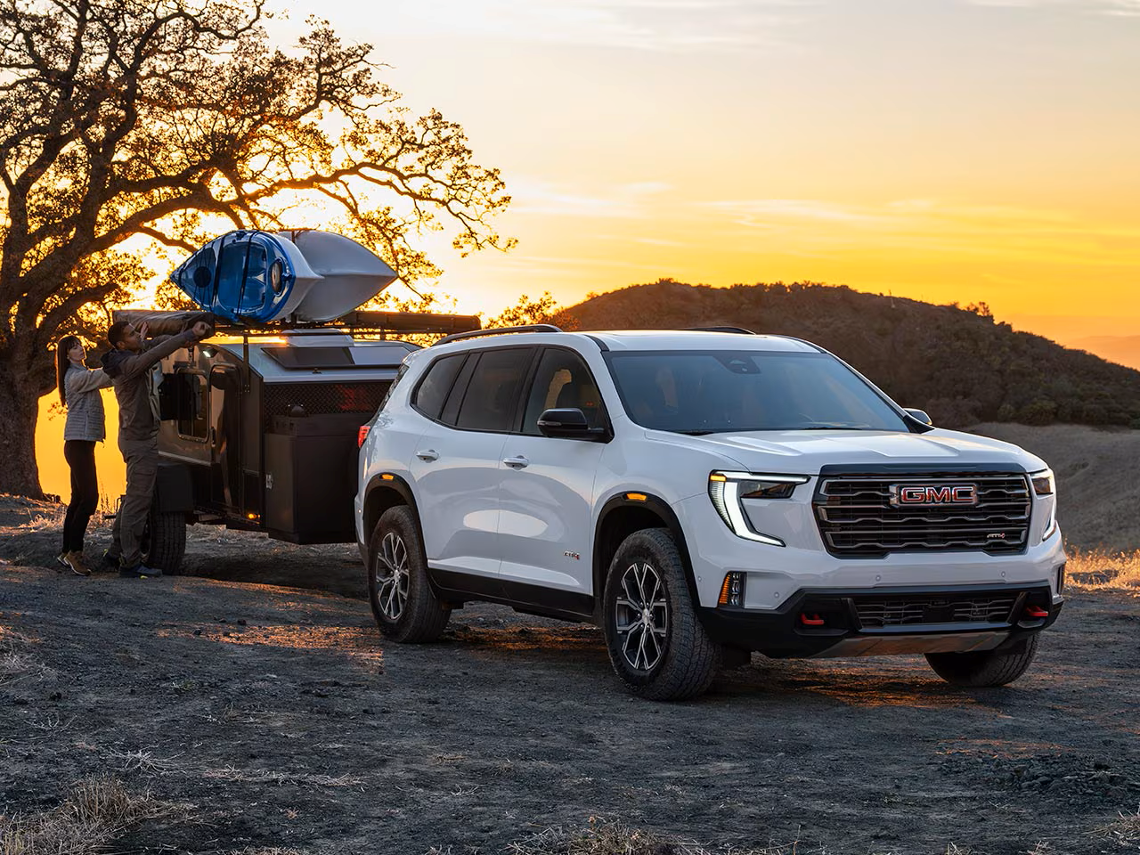 2026 GMC Acadia towing a trailer with two people outside